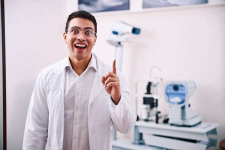 Astonished eye doctor pointing upwards with his forefinger