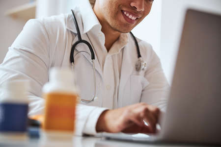Handsome confident therapist chatting with patient while surfing internet in medcial centerの写真素材