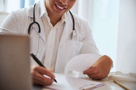 Handsome man doctor working with documents in the cabinet with special tool on his shoulderの写真素材