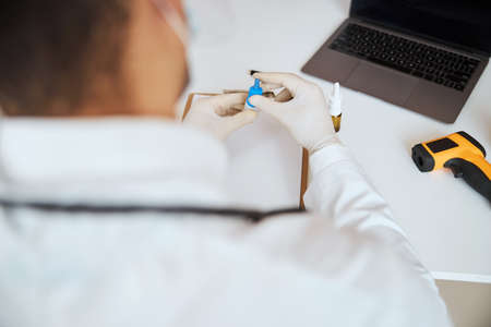 Focused image of doctor arms with medical drug in it in front of the modern deviceの写真素材