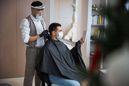 Unrecognized man with dark hair visiting barber shop while getting new hair stylingの写真素材