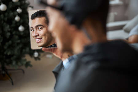 Happy smiling man with beautiful smile admiring his new hair style in beauty salon