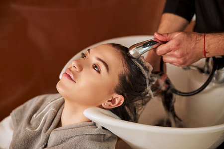 Pensive calm woman dreaming during the hairwash procedureの写真素材
