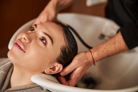 Pleased lady getting her hair washed by a hairdresserの写真素材
