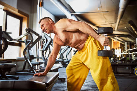 Mature bodybuilder exercising with set of dumbbellsの写真素材