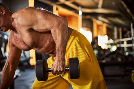Fit body-builder doing arm exercises with dumbbells