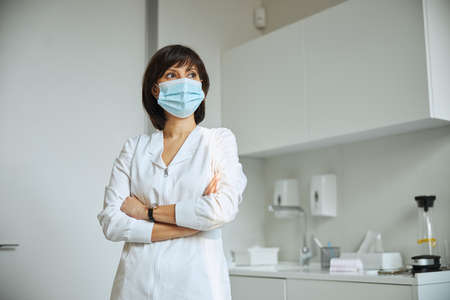 Thoughtful therapeutist in a face mask staring awayの写真素材