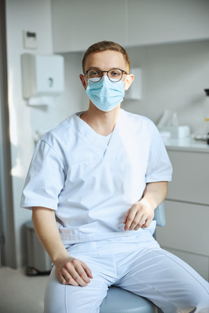 Healthcare worker in eyeglasses seated at his officeの写真素材