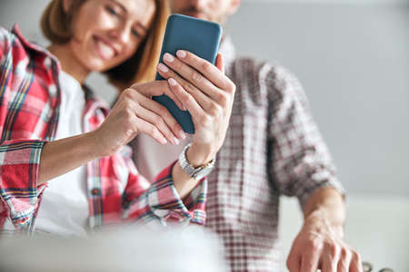 Merry lady photographing herself and her colleague in the workplaceの写真素材
