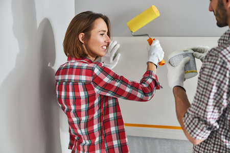 Female painter watching her colleague opening a paint bucket