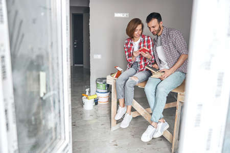 Two focused young workers analyzing building materials