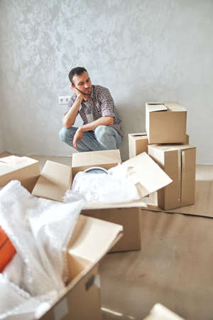 Low-spirited young man sitting in his new flatの写真素材