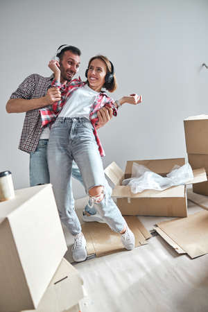 Joyous wife and her husband dancing in their new flat