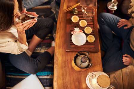 Charming young woman smelling tea leaves in cafe