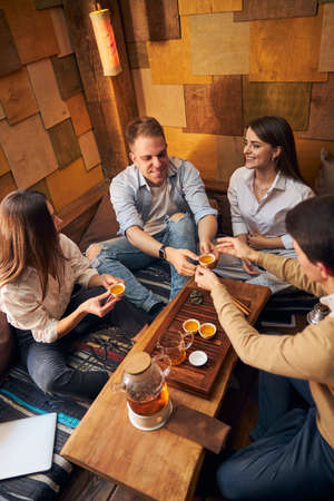 Cheerful young people enjoying tea ceremony in cozy cafe
