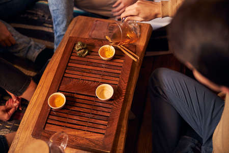 Male hand pouring herbal tea into cup in cafeの写真素材
