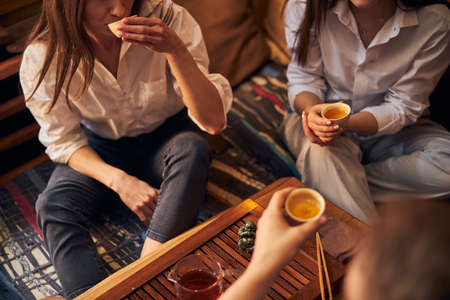 Young people drinking tea in cozy cafeの写真素材