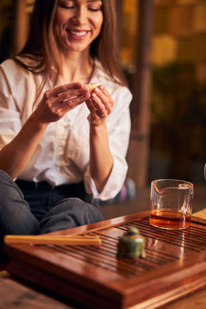 Cheerful young woman enjoying tea ceremony in cafeの写真素材