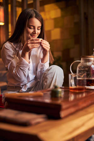 Charming young woman drinking tea in cafeの写真素材