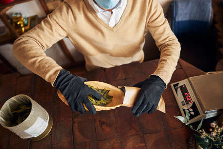 Male worker putting tea leaves into kraft paper pouch