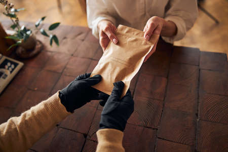 Male hands giving paper pouch to young womanの写真素材
