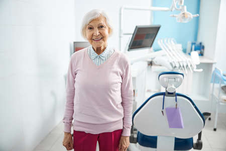 Female pensioner standing next to a dentist chair