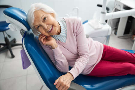Elderly female lying on her side on dentist armchairの写真素材