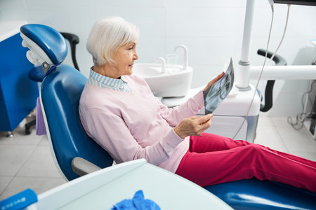 Concentrated aging lady is studying her x-ray