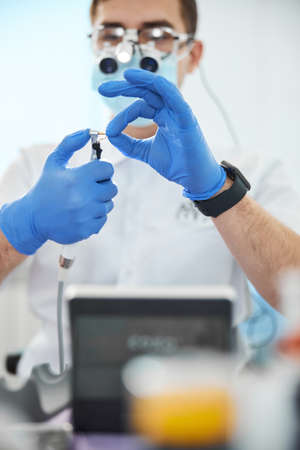 Orthodontist focused on replacing a bur of dental drill