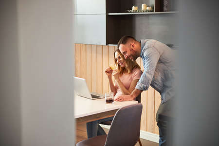 Happy young couple using modern laptop at home