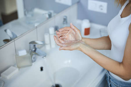 Young woman washing hands on bathroom at homeの写真素材