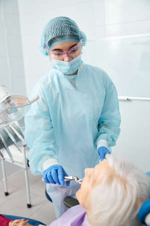 Experienced stomatologist grabbing a tooth with extracting forcepsの写真素材