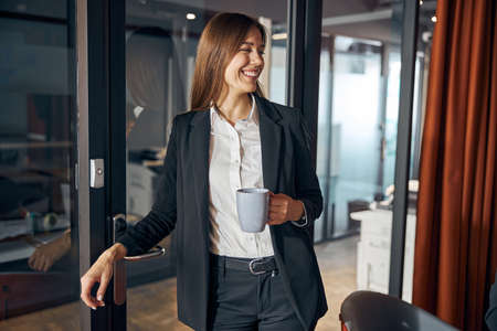 Merry businesswoman with a beverage looking awayの写真素材