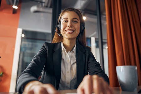 Pleased young office worker typing on her laptopの写真素材