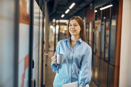 Happy female employee daydreaming during her coffee break