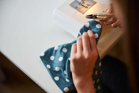 Female child hands cutting thread in sewing workshopの写真素材