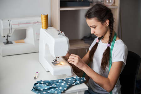 Cute girl sewing clothes in dressmaking studioの写真素材