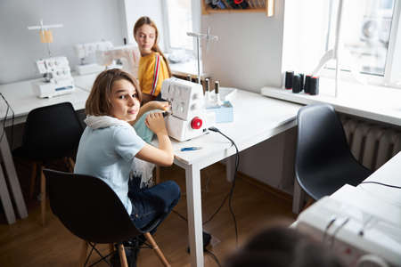 Adorable girls sewing clothes in dressmaking studioの写真素材
