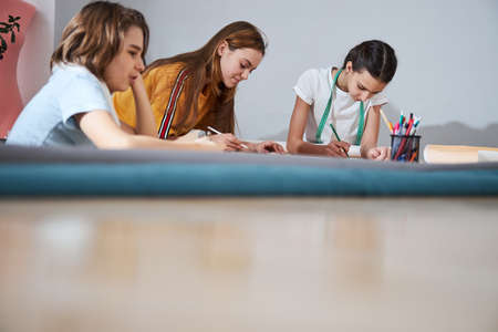 Adorable girls making sewing patterns in workshopの写真素材