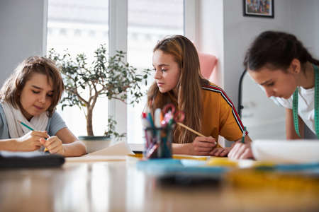 Adorable female kids drafting sewing patterns in workshop