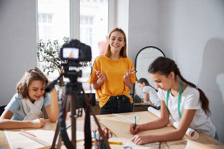 Joyful female children recording video in sewing workshopの写真素材