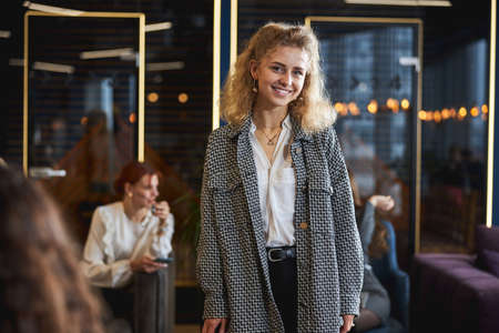 Cheerful young woman standing in modern office