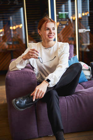 Charming young woman sitting on couch in office