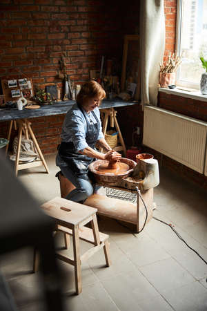 Nice female potter making pottery in workshop