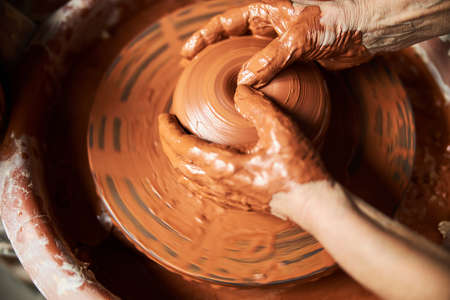Potter hands making clay pot on pottery wheel