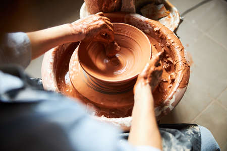 Female potter hands making clay pot in pottery studio