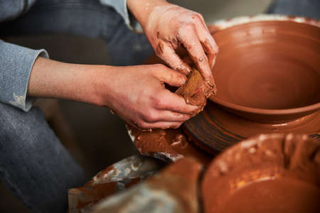 Potter hands making clay bowl on pottery wheel