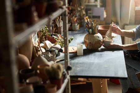 Female ceramic artist painting pottery in workshop