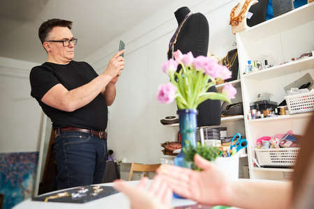 Handcrafter taking photos of his jewelry items with a smartphone