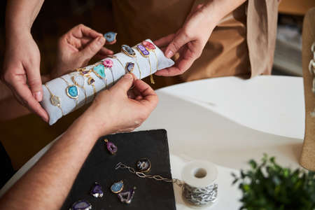 Artisan picking the right gemstone bracelets for his earringsの写真素材